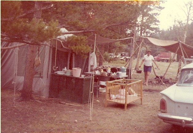 July 1963. Carol was just a year old. There's the tent and all of Dad's tarps. He set up quite a campground. (That's Mom hauling hot water for something)